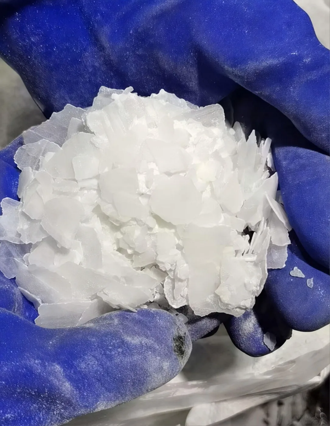 Caustic Soda Flakes Closeup with Protective Gloves